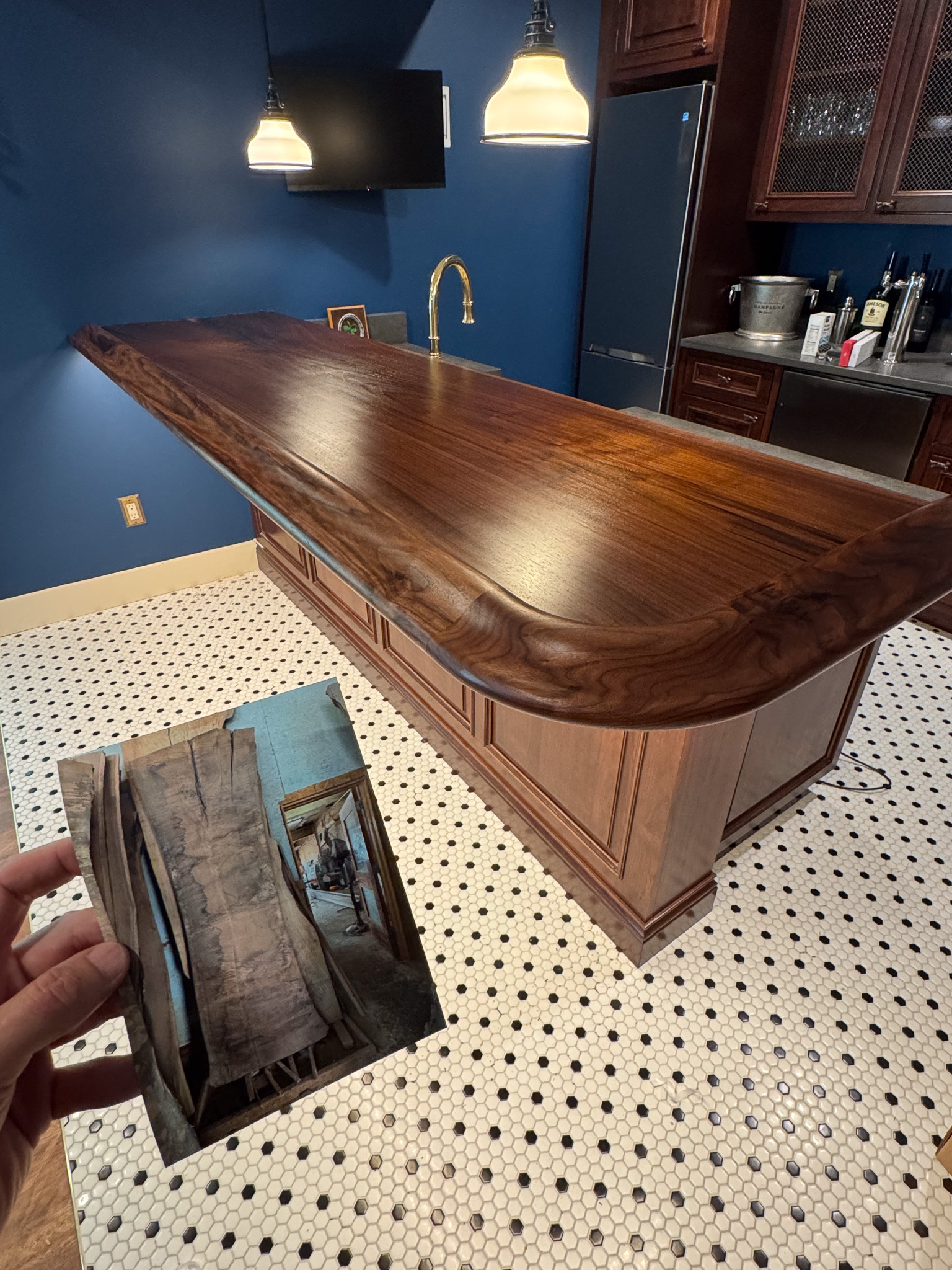 Live-edge walnut bar top installed in a private home, with the raw slab it was cut from shown in an inset photograph held in the foreground